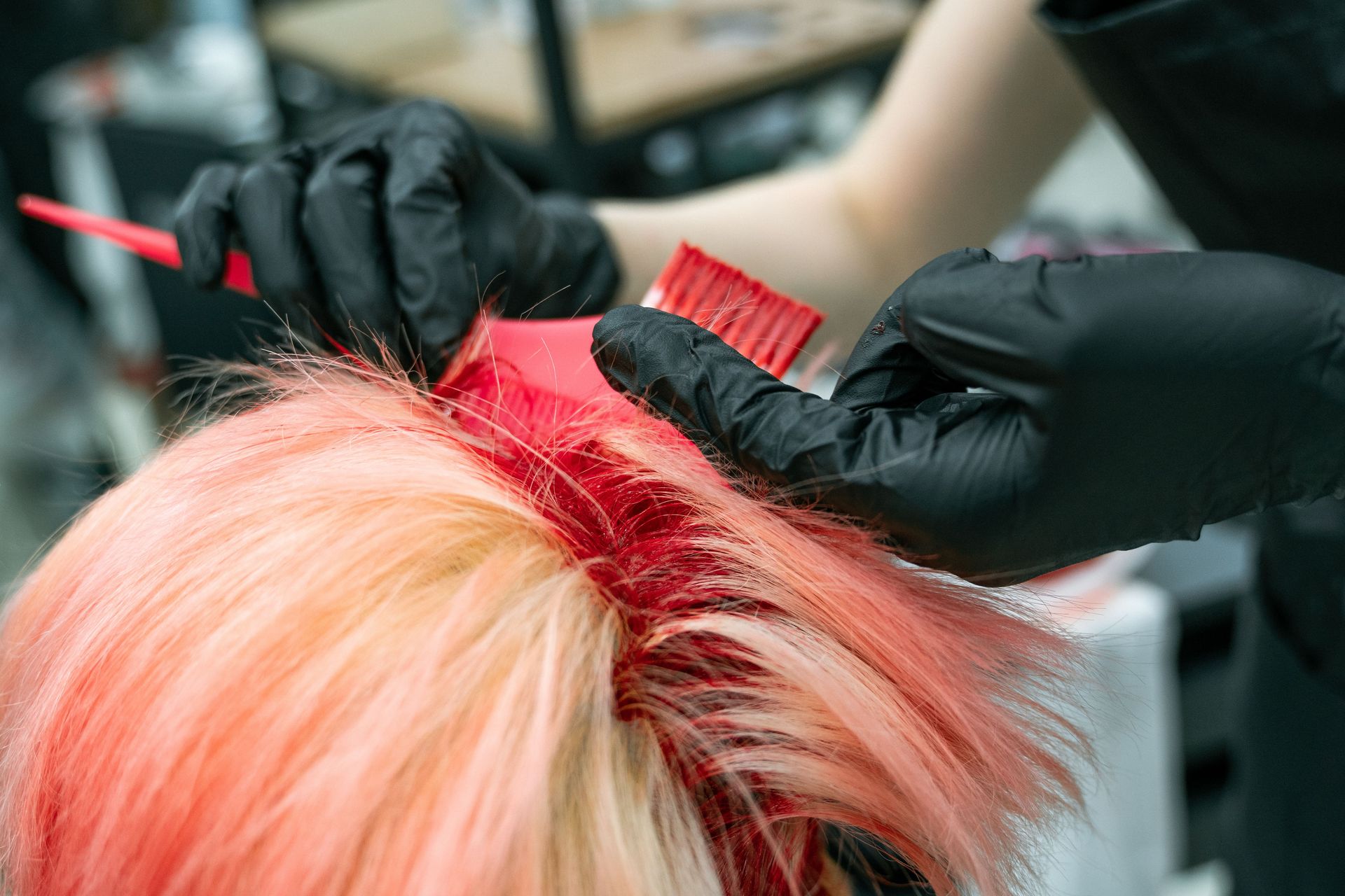 Close-up of vibrant hair coloring process with gloved hands applying dye.
